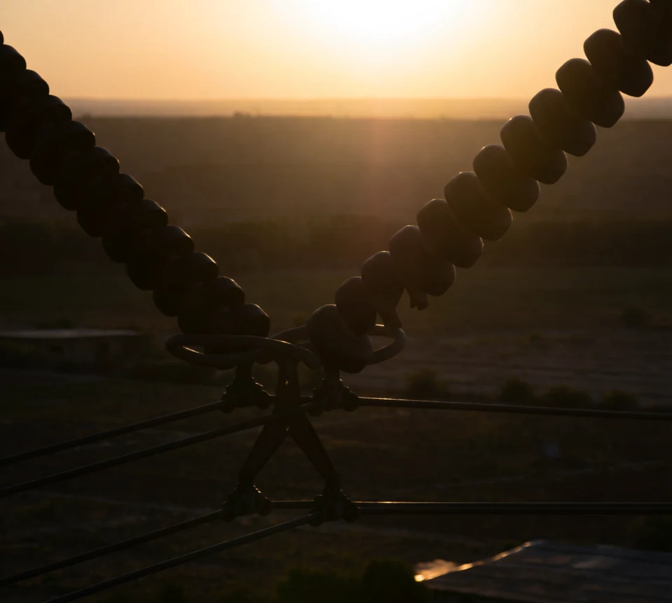 Low sun behind inspection hardware at Close aerial insulator and conductor inspection, generated by our world model